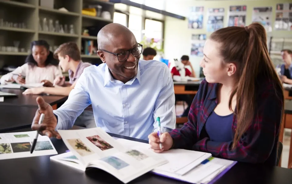 high school tutor sitting at desk with female BKHVWRX